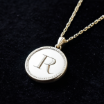 **

A close-up shot of a silver pendant necklace with initials elegantly engraved. The necklace is displayed on a dark velvet background, highlighting the intricate details of the lettering. The lighting is soft and diffused, creating a sense of timeless elegance. safe for work, appropriate content, fully clothed, professional jewelry photography, perfect anatomy, natural proportions, high quality.

**